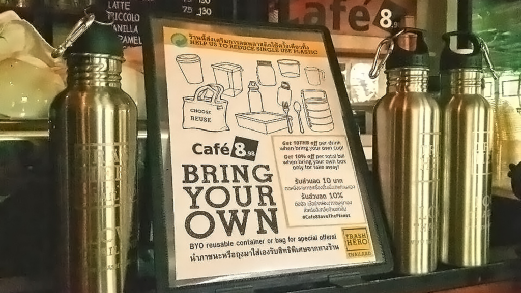 Trash Hero-Flaschen neben einem Schild in einem Café mit der Aufschrift "Bring your own".