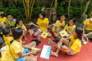 group of kids sitting on the floor with trash hero books and trash hero t-shirts
